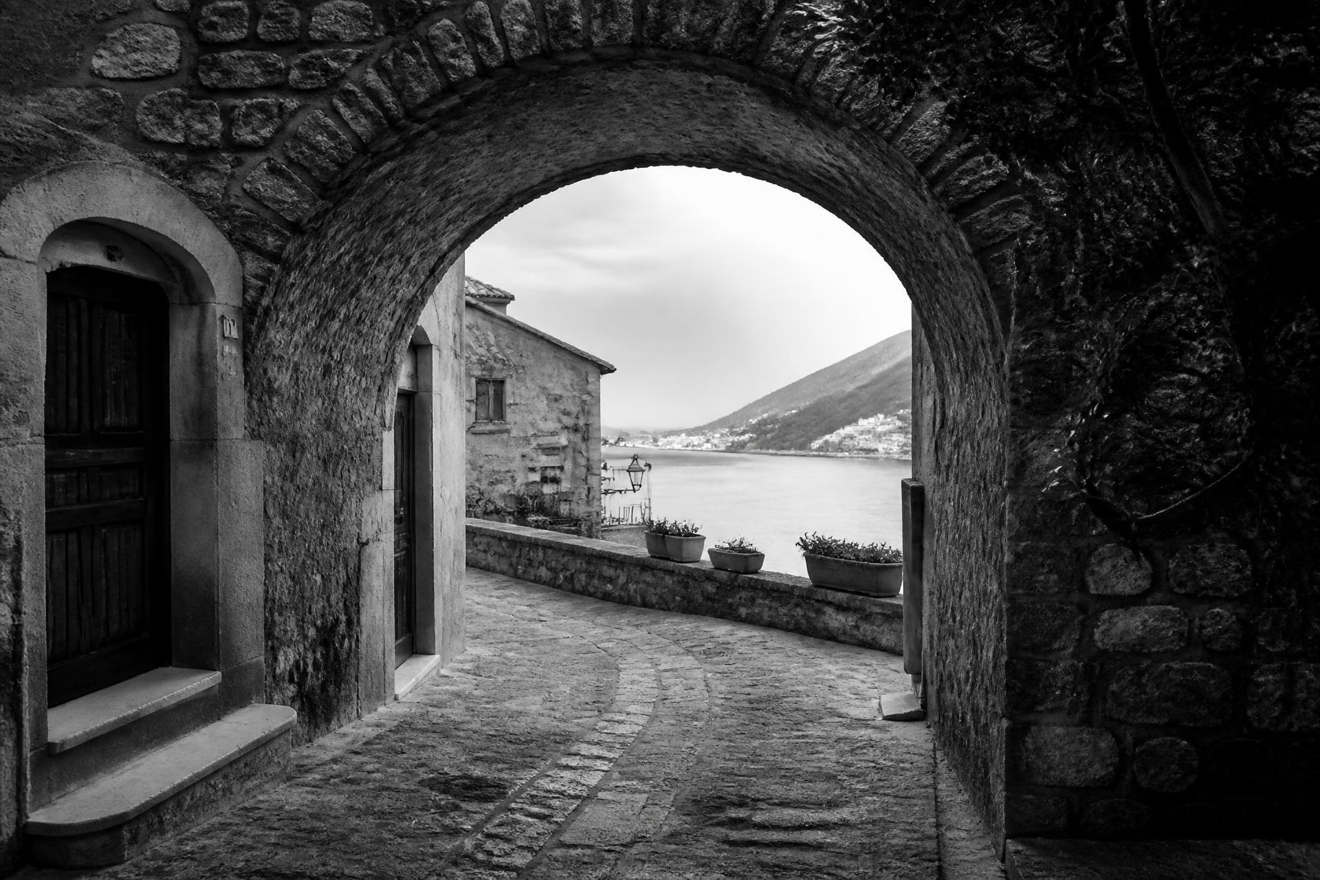 Black and white photograph of a Mediterranean stone archway opening to the sea